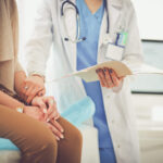 Doctor checking report and patient