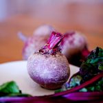 a beet and beet greens on a white plate
