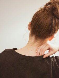 A woman rubs her shoulder in discomfort