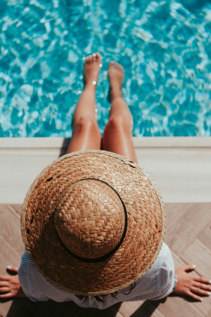woman sitting by the pool with legs in water